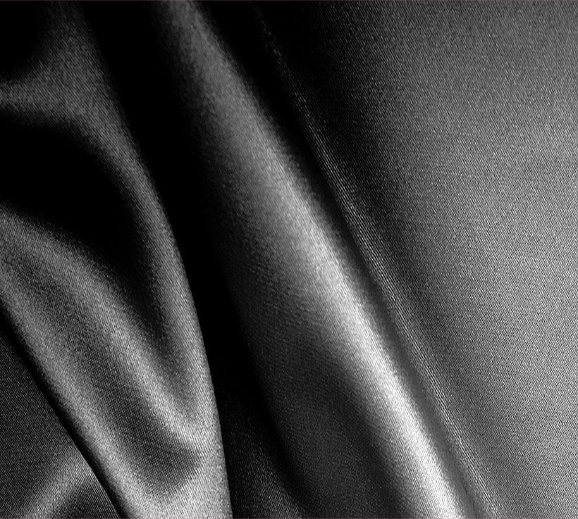 Black satin-finish knitted fabric in soft folds
